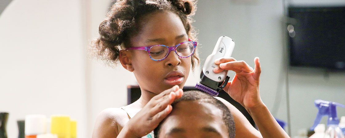 a young girl using clippers to a give a boy a haircut