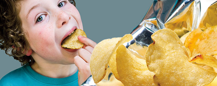 a boy eating from a bag of potato chips
