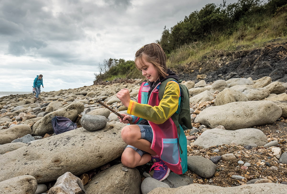 Photo of a kid looking for bones on a beach