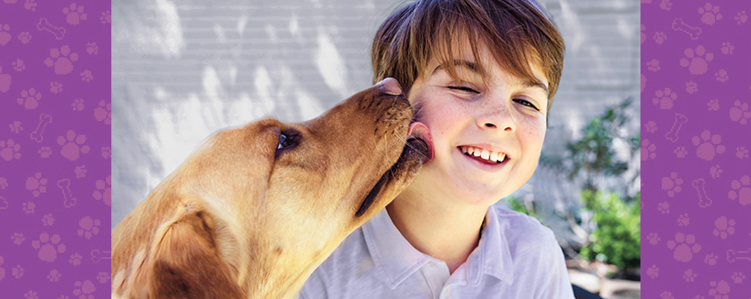 Photo of a dog licking a child&apos;s cheek